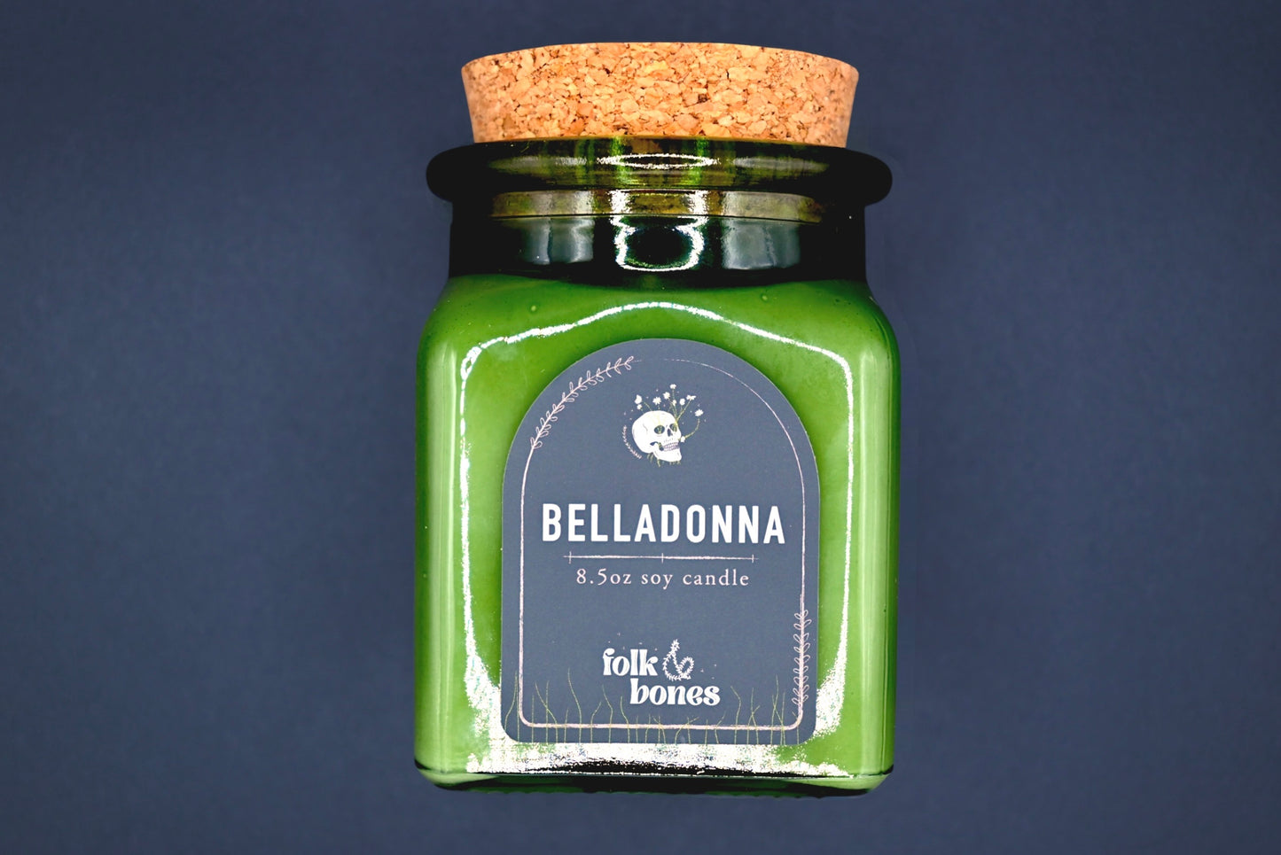 Folk and Bones Belladonna 8 oz soy candle in a glass jar with a lit wick and decorative label, ideal for home ambiance.