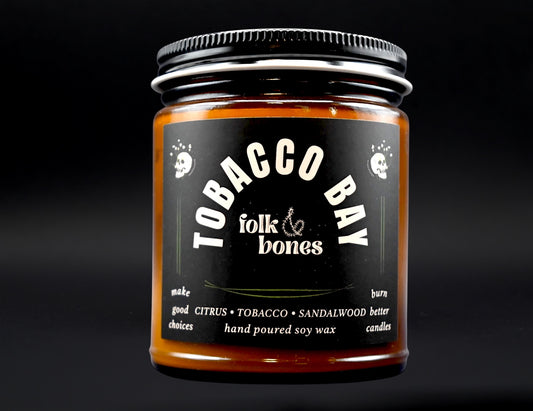 Folk and Bones Tobacco Bay 8 oz soy candle in a glass jar with a natural wick, showcasing its warm, rustic design.