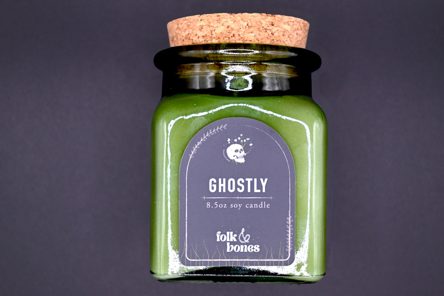 Folk and Bones Ghostly 8 oz soy candle in a glass jar with a black lid, featuring a spooky ghostly design on the label.