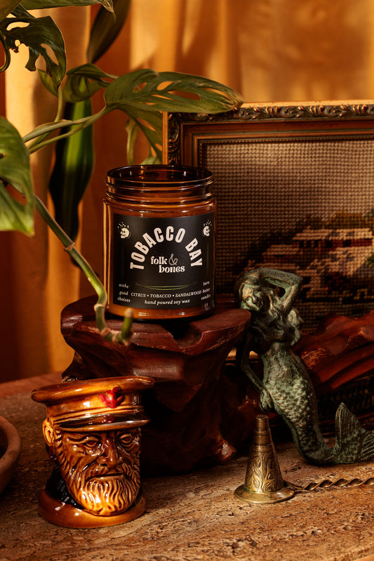 Folk and Bones Tobacco Bay 8 oz soy candle with a rustic jar and natural wax, ideal for home fragrance and cozy ambiance.