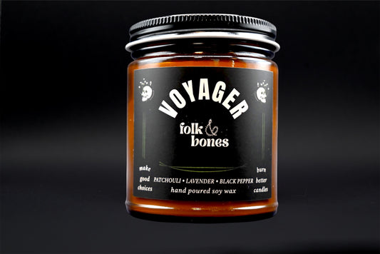 Folk and Bones Voyager 8 oz soy candle in a glass jar with a lit wick and minimalist label on a neutral background.