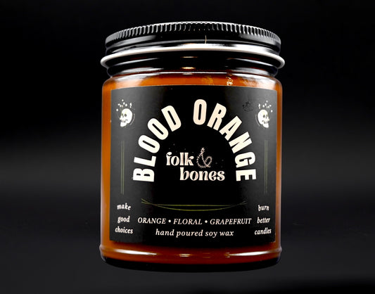Folk and Bones blood orange soy candle in an 8 oz container, featuring a warm, citrus scent and a natural wax finish.