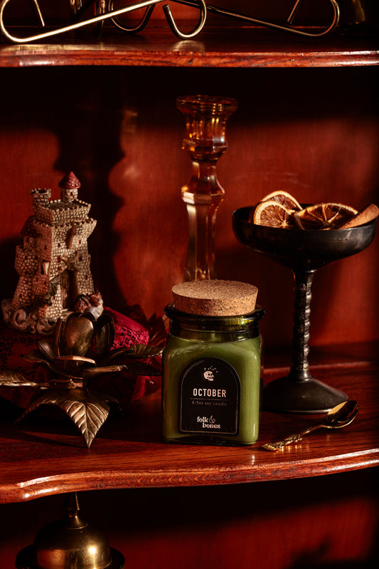 Folk and Bones October 8 oz soy candle in a glass jar with a wooden lid, featuring a warm autumn-themed label.