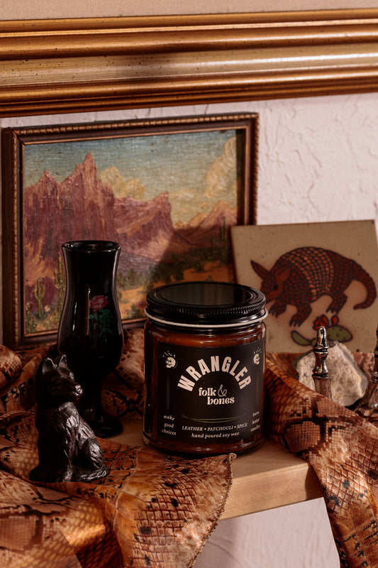 Wrangler Folk and Bones 8 oz soy candle in a glass jar with a natural wick, perfect for home decor and ambient lighting.