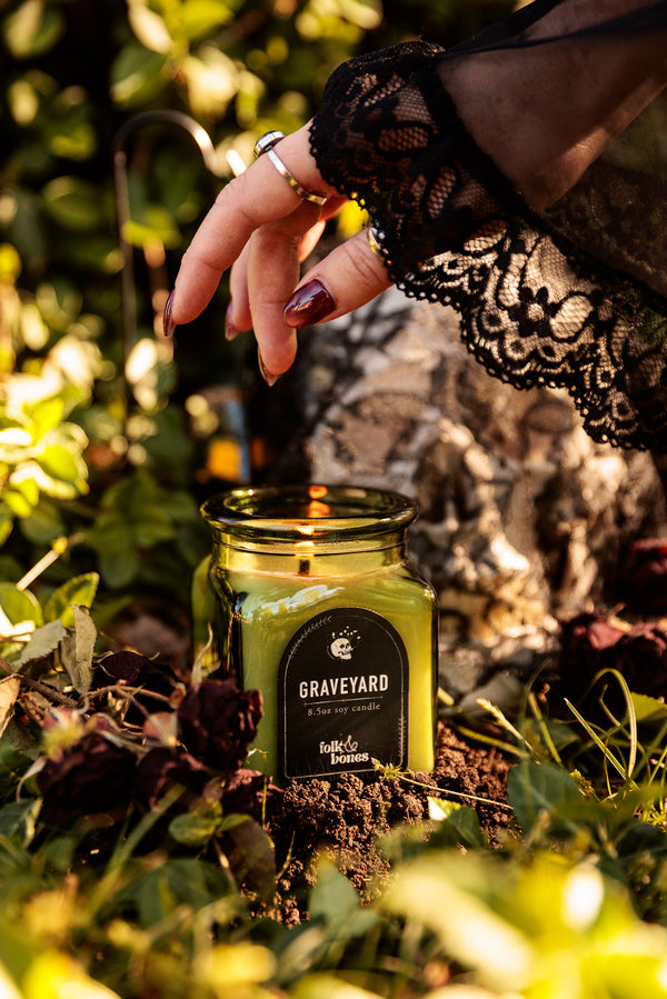 Folk and Bones Graveyard 8 oz soy candle in a dark jar with spooky label, ideal for gothic or Halloween decor.