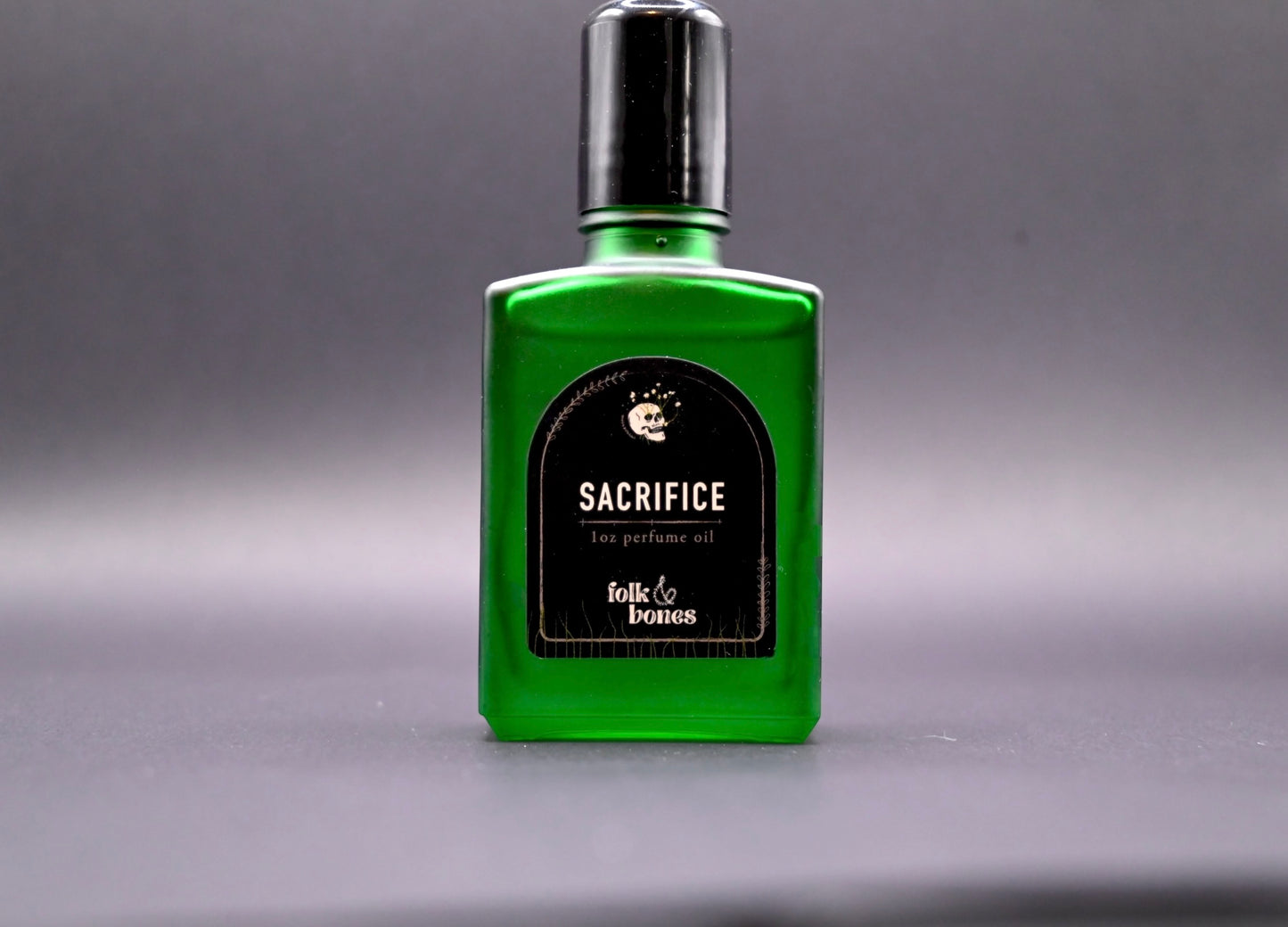 Folk and Bones Sacrifice 1 oz perfume oil candle with dark wax and botanical accents in a glass container.