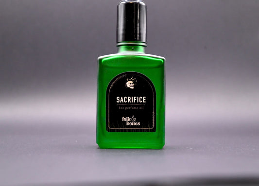 Folk and Bones Sacrifice 1 oz perfume oil candle with dark wax and botanical accents in a glass container.