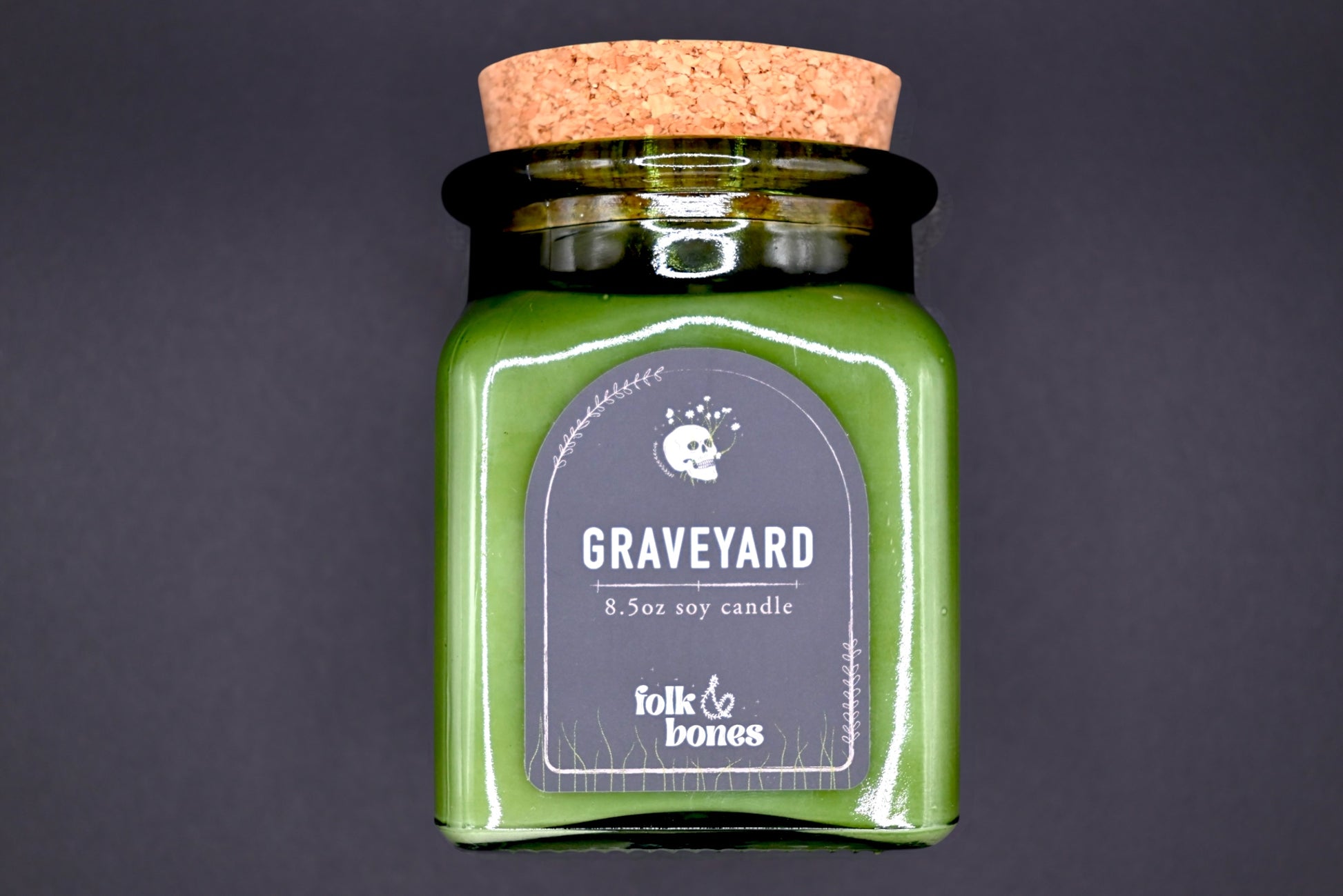 Folk and Bones Graveyard 8 oz soy candle in a dark jar with a spooky label, suitable for gothic or gothic-inspired decor.