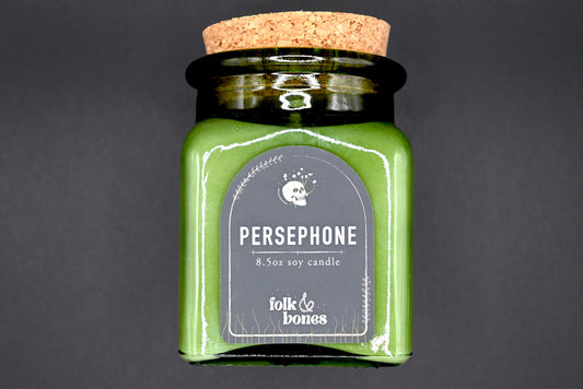 Persephone 8 oz soy candle by Folk and Bones, showing a lit candle in a glass jar with a minimalist label design.