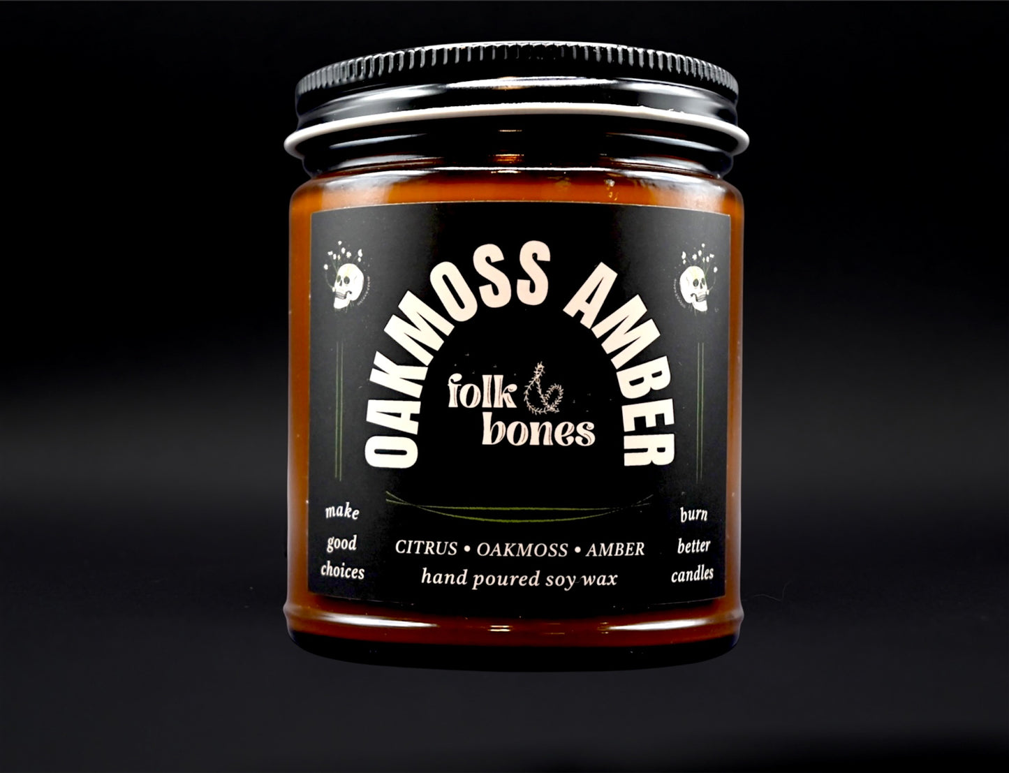 Folk and Bones Oakmoss Amber soy candle in an 8 oz glass jar with a lit wick, showcasing a cozy, earthy ambiance.