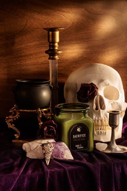 Folk and Bones Sacrifice 8 oz soy candle in a glass jar, featuring a natural wax finish and a clean-burning wick.