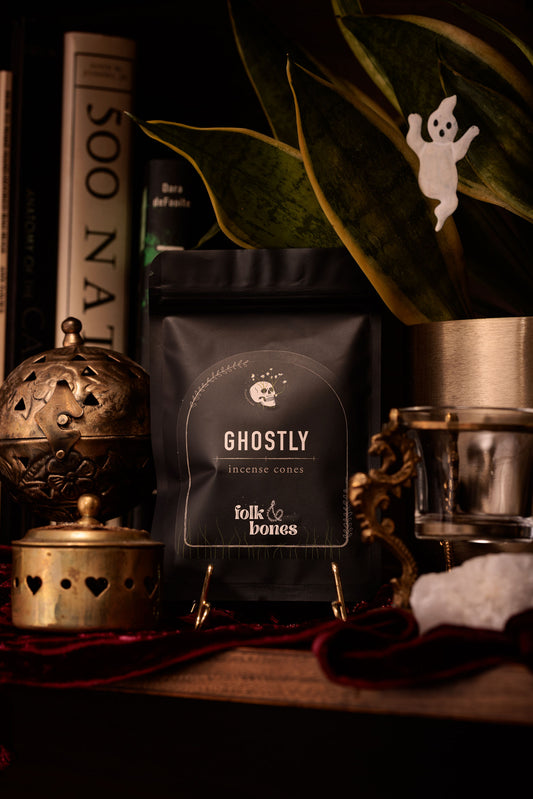 Folk and Bones Ghostly incense cones, candle-like package with dark, mystical design, used for aromatic incense burning.