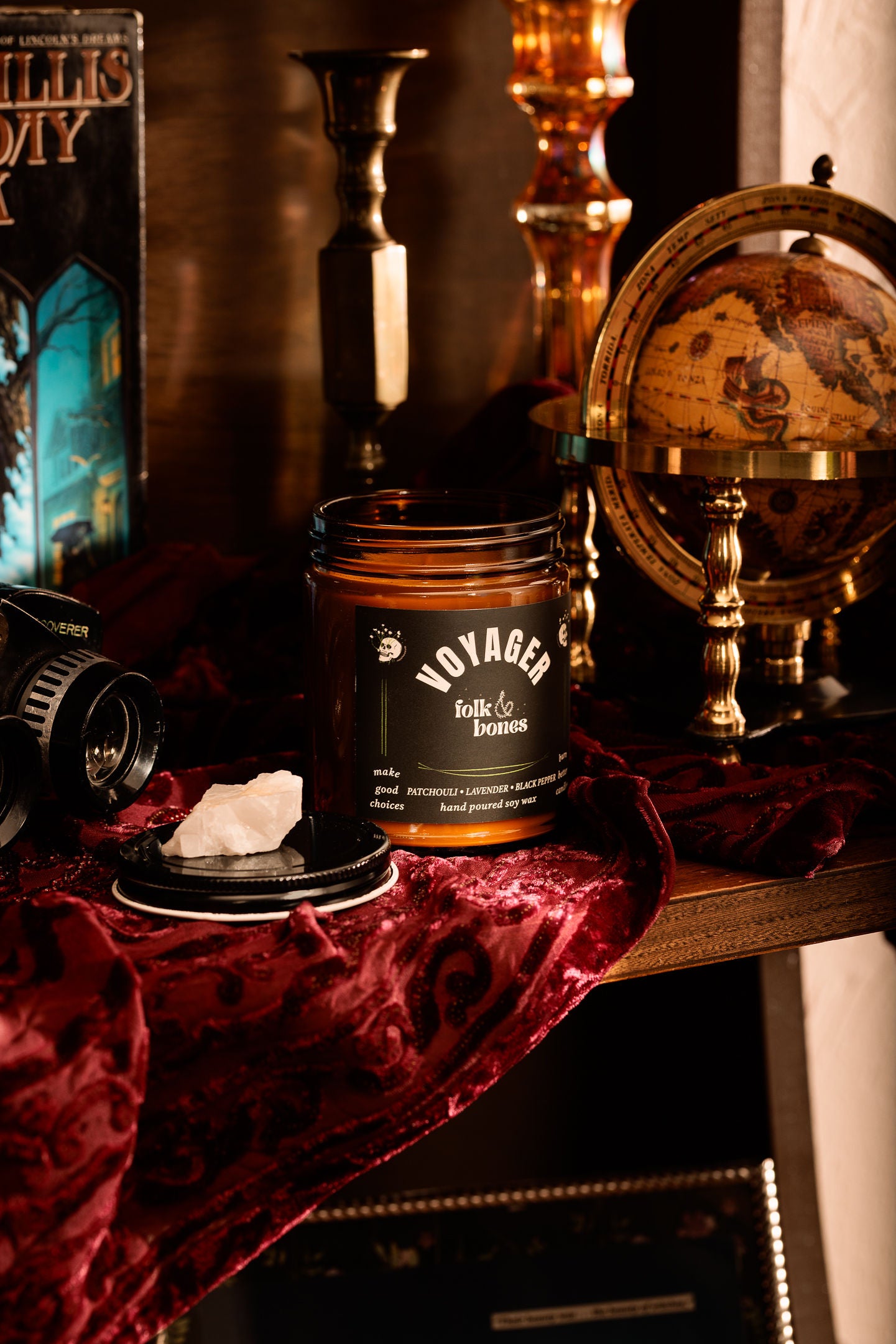 Folk and Bones Voyager 8 oz soy candle in a glass jar, showing the lit candle with soft wax and a warm glow.