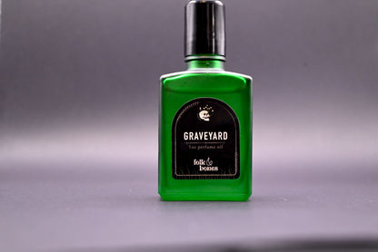 Folk and Bones Graveyard 1 oz perfume oil candle with dark, gothic design and eerie label, set against a black background.