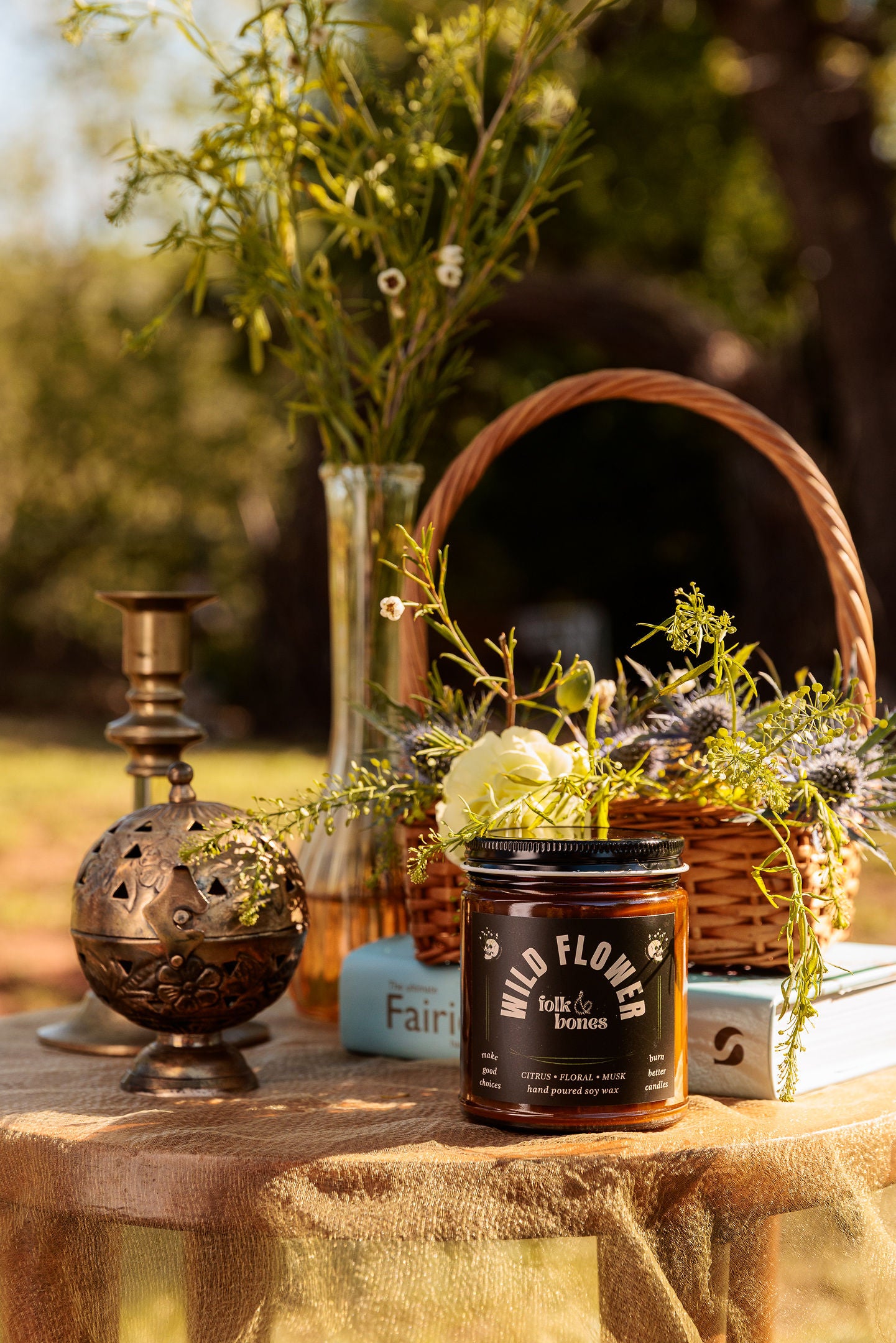 Folk and Bones Wild Flower 8 oz soy candle with a glass jar, featuring a natural floral design and a lit wick for cozy ambiance.