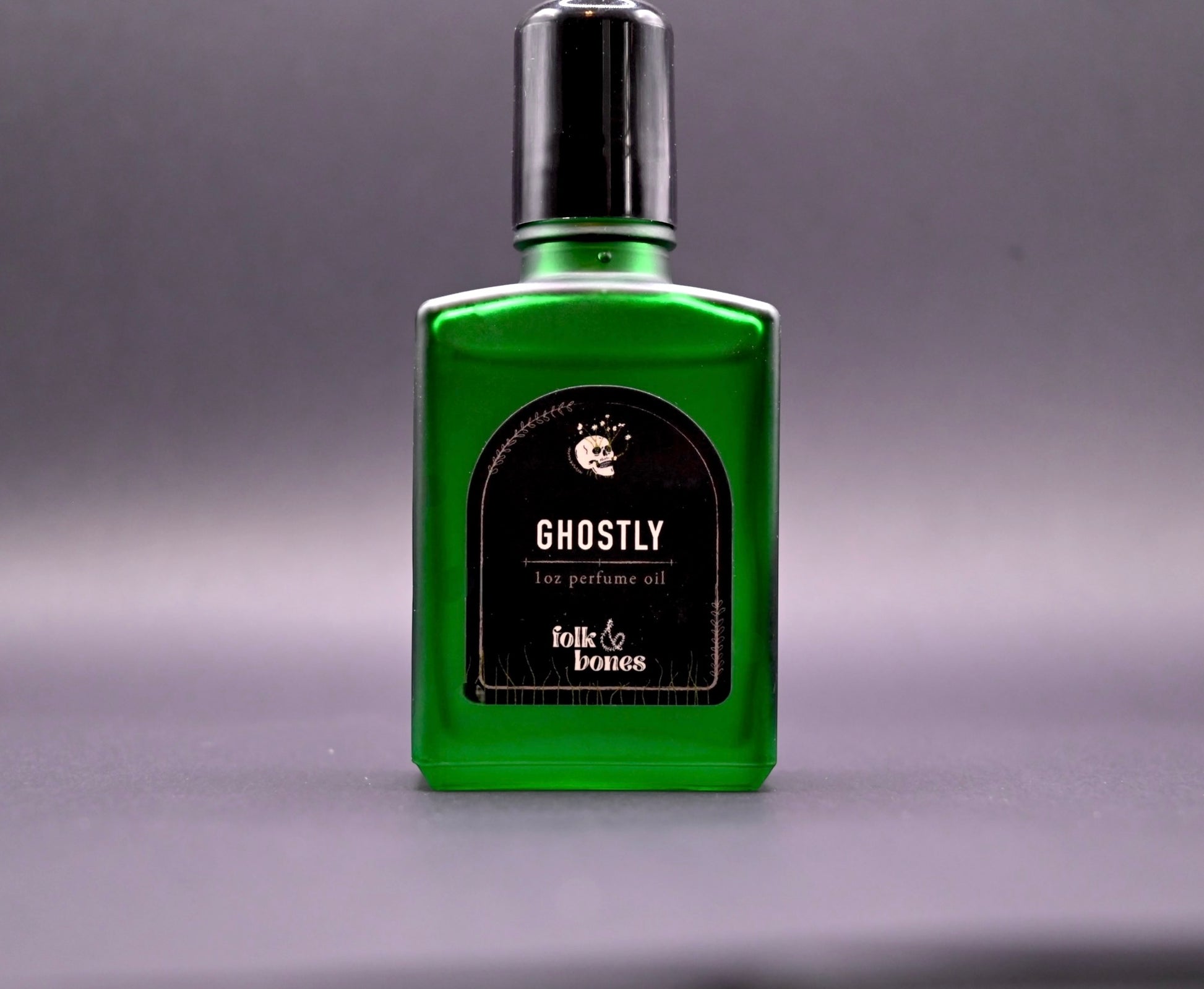 Folk and Bones Ghostly 1 oz perfume oil bottle with black cap, displayed on a neutral surface.